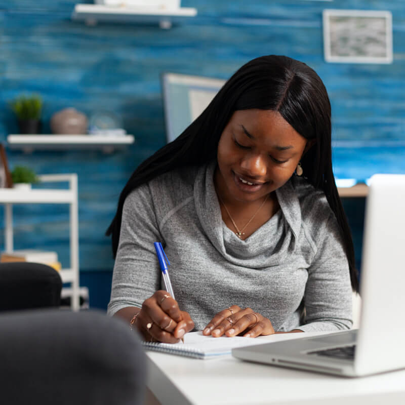 women watching the tscs webinar on laptop and taking notes